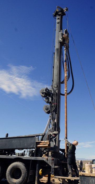 A technician working on a well drilling rig, adding a section of drill steel