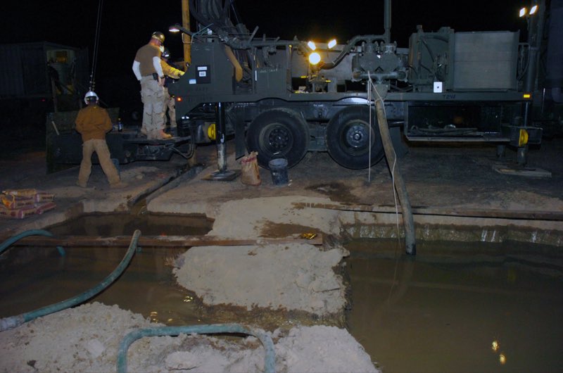 A crew operating a water well drilling rig
